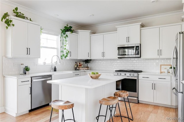 kitchen with a kitchen island, a breakfast bar, white cabinetry, sink, and stainless steel appliances