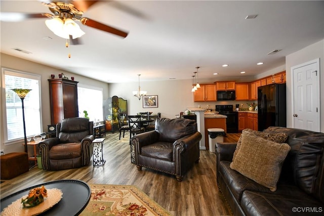 living room with hardwood / wood-style flooring and ceiling fan with notable chandelier