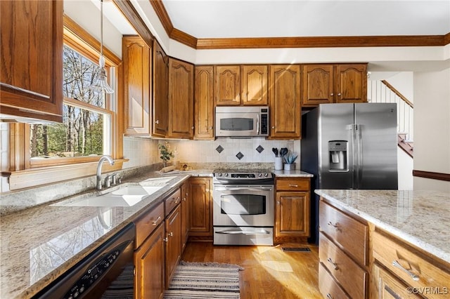 kitchen with appliances with stainless steel finishes, tasteful backsplash, light hardwood / wood-style floors, ornamental molding, and sink