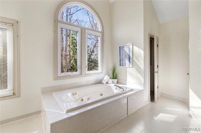 bathroom with lofted ceiling, tile patterned flooring, and tiled tub