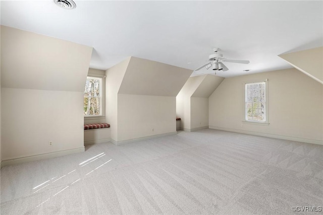 additional living space with ceiling fan, lofted ceiling, light colored carpet, and plenty of natural light