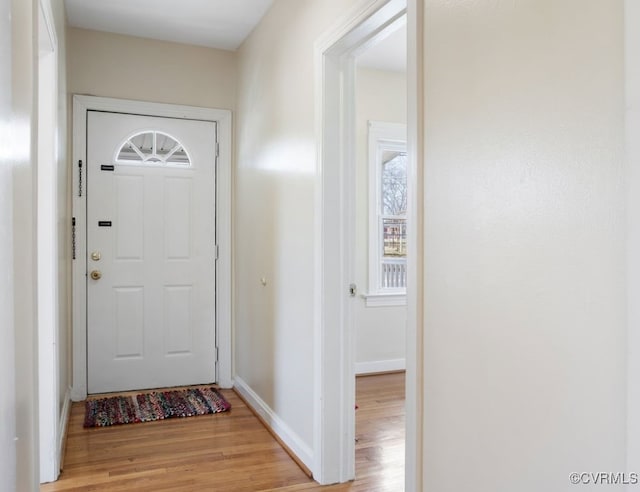 doorway with light wood finished floors and baseboards