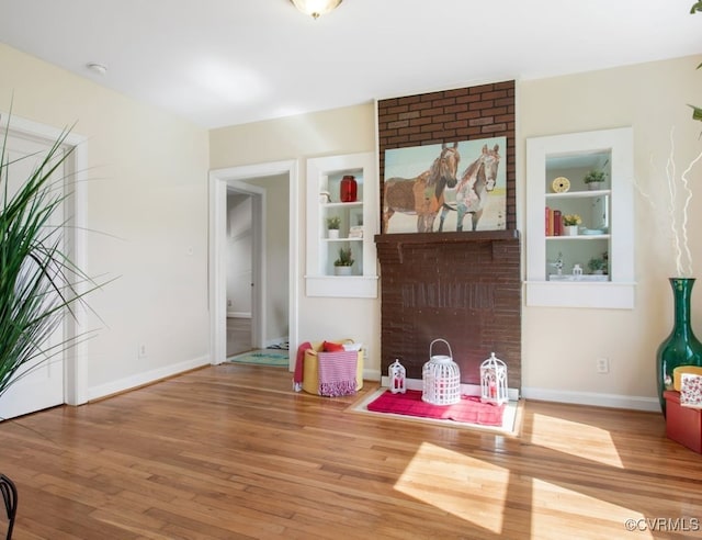 interior space featuring built in shelves, baseboards, and wood finished floors