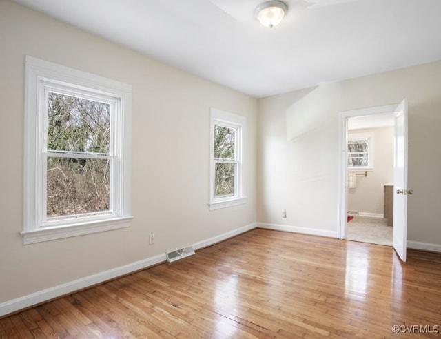 unfurnished room featuring light wood-style flooring, visible vents, and baseboards