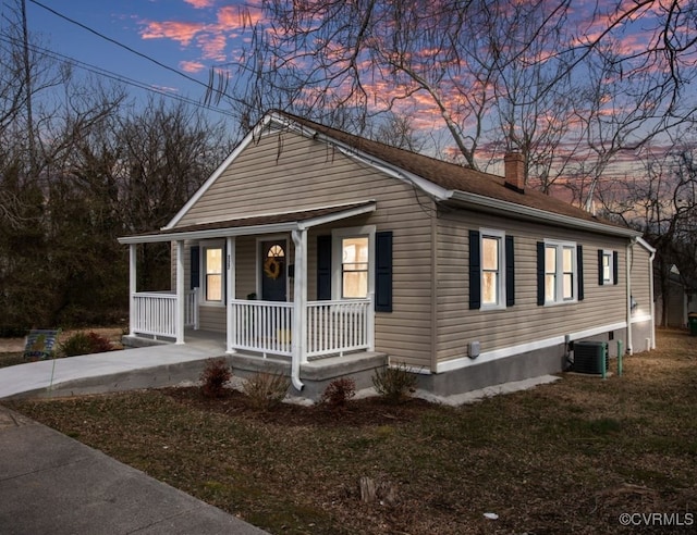 view of front of property featuring a porch, a chimney, and central AC unit