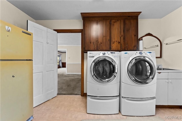 laundry area with light colored carpet, cabinet space, a sink, and washing machine and clothes dryer