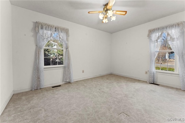 unfurnished room with a wealth of natural light, visible vents, and light colored carpet