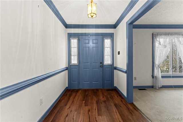 foyer entrance with baseboards, visible vents, and crown molding