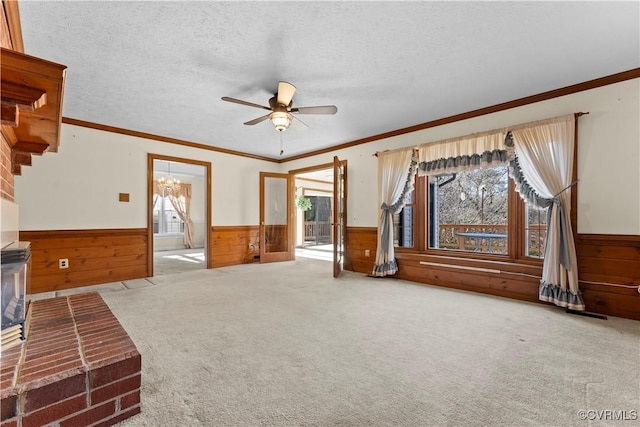 unfurnished living room featuring a wainscoted wall, a textured ceiling, ceiling fan with notable chandelier, and carpet flooring