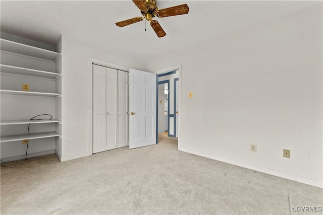 unfurnished bedroom with light carpet, a closet, a ceiling fan, and baseboards