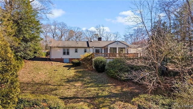 back of house featuring a chimney, a lawn, and a wooden deck