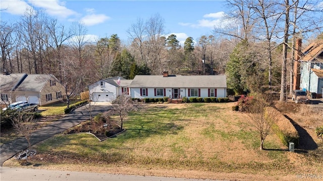 single story home featuring a front yard, driveway, a chimney, and an attached garage