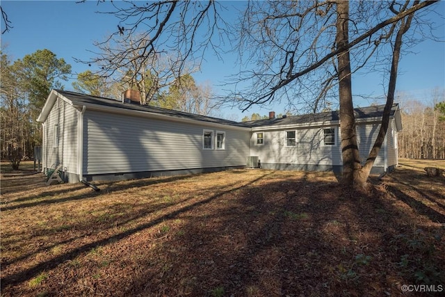 rear view of house with cooling unit and a lawn