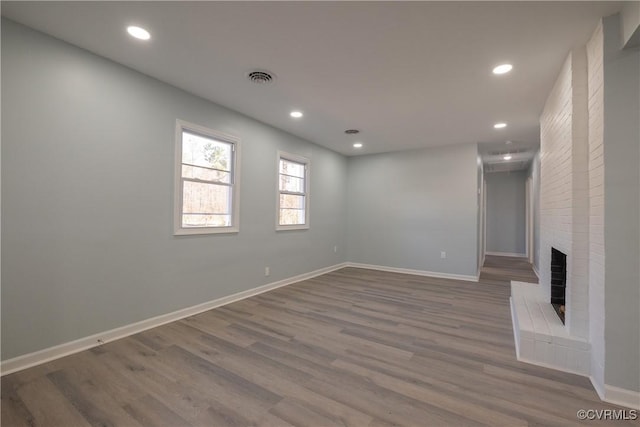 unfurnished living room featuring a brick fireplace and dark wood-type flooring