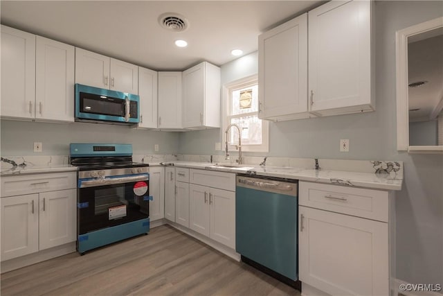 kitchen featuring white cabinetry, sink, light stone counters, light hardwood / wood-style floors, and stainless steel appliances