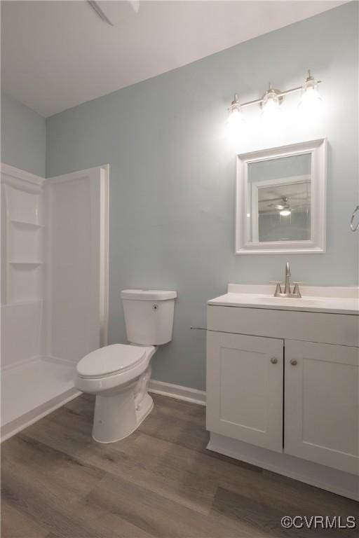 bathroom with wood-type flooring, vanity, walk in shower, and toilet