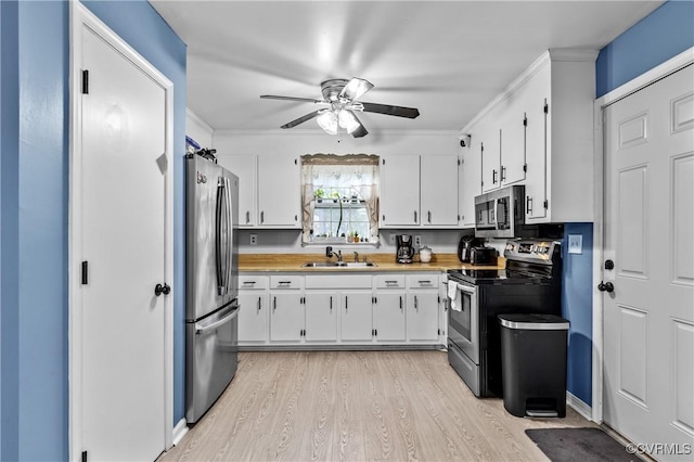 kitchen featuring appliances with stainless steel finishes, sink, white cabinets, ceiling fan, and light hardwood / wood-style floors