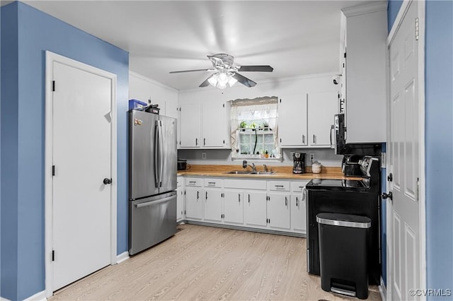 kitchen with butcher block counters, stainless steel refrigerator, black range with electric cooktop, light hardwood / wood-style floors, and white cabinets