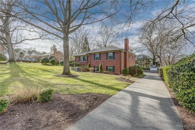 view of front facade with a front lawn, a chimney, and brick siding