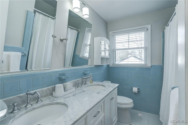 bathroom featuring a sink, tile walls, toilet, and double vanity