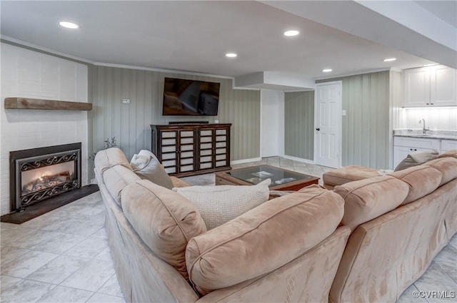 living room with recessed lighting, a large fireplace, and crown molding