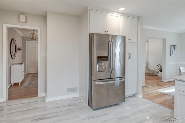 kitchen featuring light countertops, stainless steel fridge, visible vents, and white cabinets