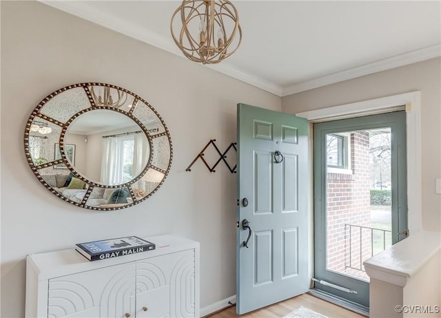 foyer entrance featuring crown molding, light wood-style flooring, baseboards, and an inviting chandelier