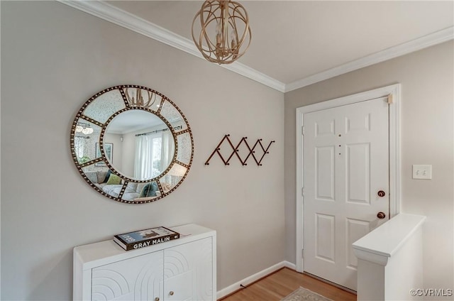 entrance foyer with baseboards, ornamental molding, a notable chandelier, and light wood-style floors