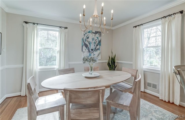 dining space featuring a healthy amount of sunlight, light wood-style flooring, visible vents, and crown molding