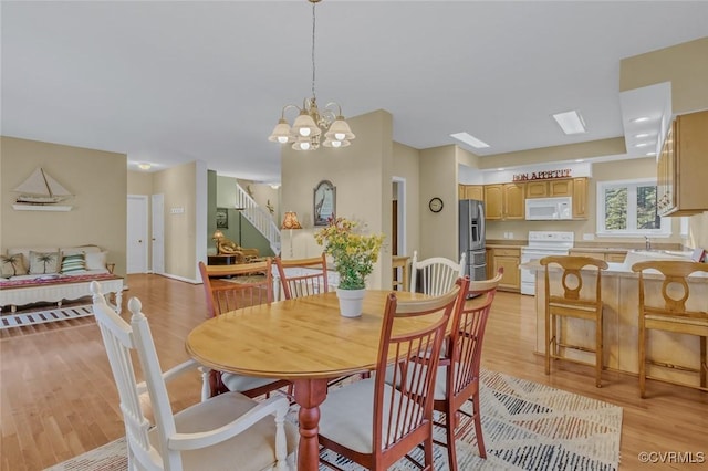 dining space featuring sink, light hardwood / wood-style flooring, and a notable chandelier