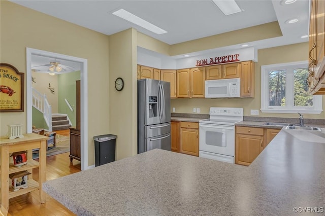 kitchen featuring a skylight, sink, light brown cabinets, white appliances, and light hardwood / wood-style flooring