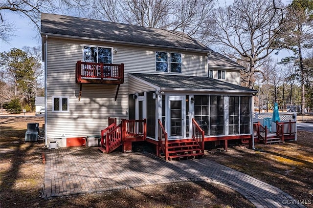 back of property featuring a balcony, a patio, and a sunroom