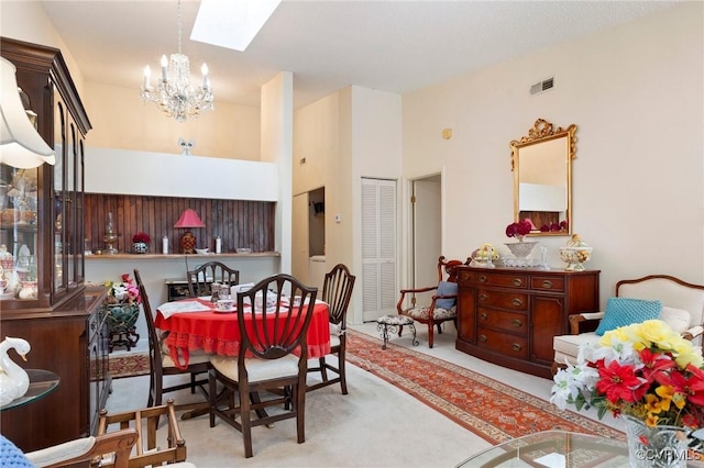 dining space with carpet, visible vents, a notable chandelier, and a skylight