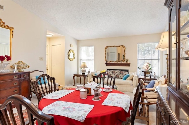 carpeted dining area featuring a wealth of natural light, visible vents, and a textured ceiling