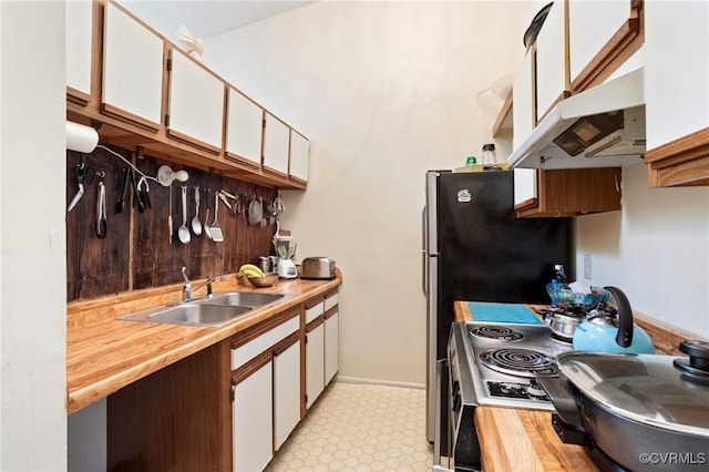 kitchen with a sink, white cabinetry, under cabinet range hood, light floors, and butcher block countertops