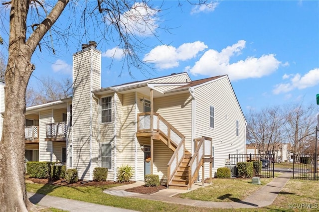 view of front of house with stairs, a chimney, and a front yard