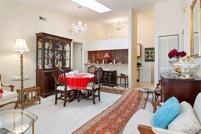 dining room with a skylight, visible vents, a towering ceiling, carpet flooring, and a chandelier