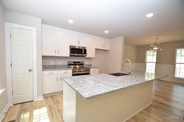 kitchen featuring a kitchen island with sink, sink, stainless steel appliances, and white cabinets