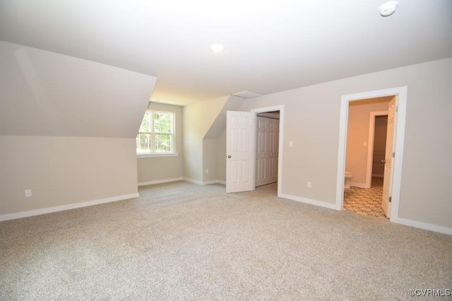 additional living space with light colored carpet and vaulted ceiling