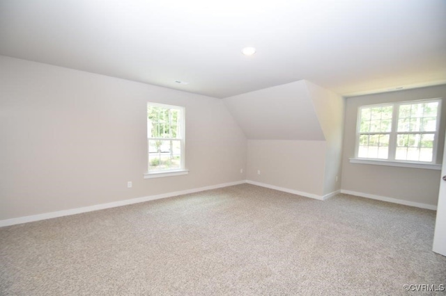 bonus room with lofted ceiling, a wealth of natural light, and light colored carpet