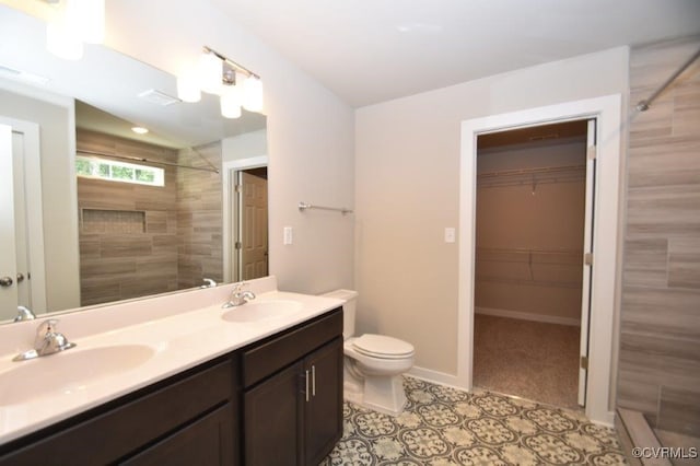 bathroom featuring vanity, tile patterned floors, toilet, and a tile shower