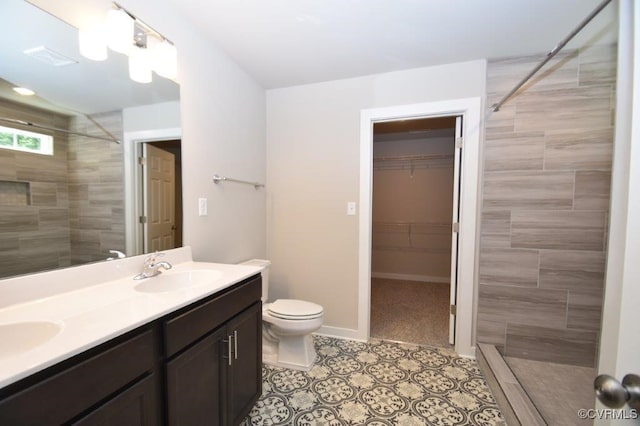 bathroom featuring vanity, tile patterned flooring, toilet, and tiled shower