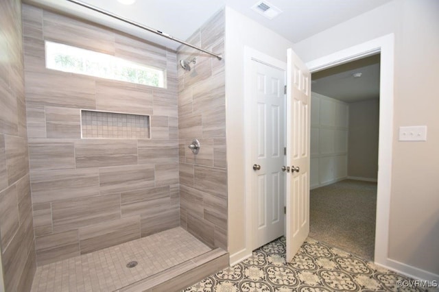 bathroom with tile patterned flooring and a tile shower