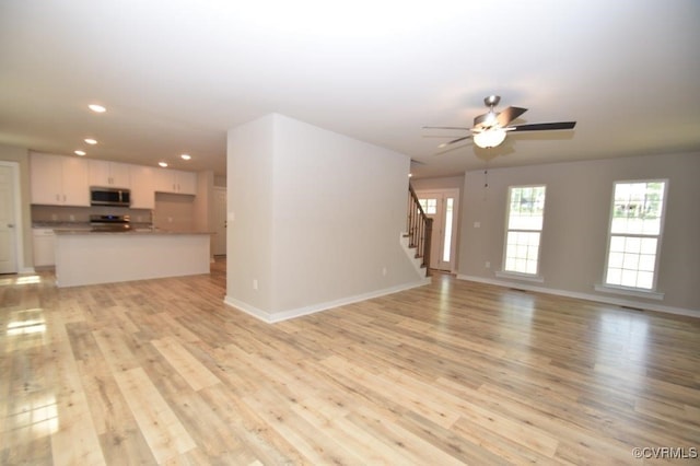 unfurnished living room with ceiling fan and light wood-type flooring