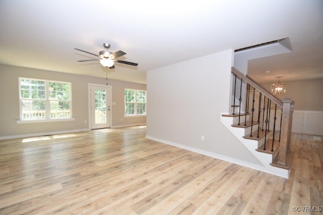 unfurnished living room featuring ceiling fan with notable chandelier and light hardwood / wood-style floors