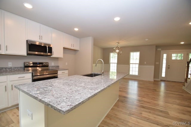 kitchen featuring a kitchen island with sink, sink, and appliances with stainless steel finishes