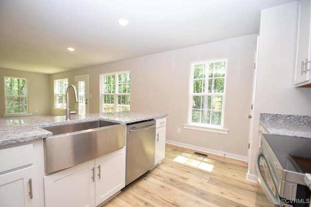 kitchen with sink, white cabinetry, light stone counters, light hardwood / wood-style flooring, and stainless steel dishwasher