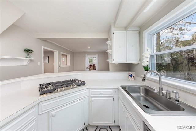 kitchen with sink, white cabinets, stainless steel gas cooktop, and kitchen peninsula