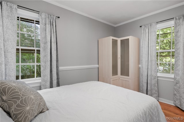 bedroom with multiple windows, crown molding, and hardwood / wood-style floors