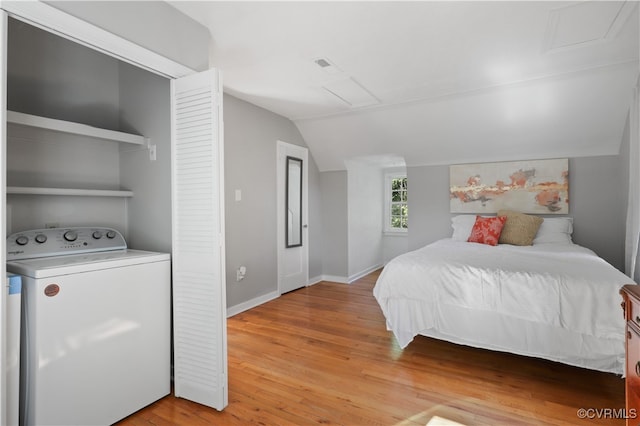 bedroom featuring washer / clothes dryer, lofted ceiling, and light hardwood / wood-style flooring